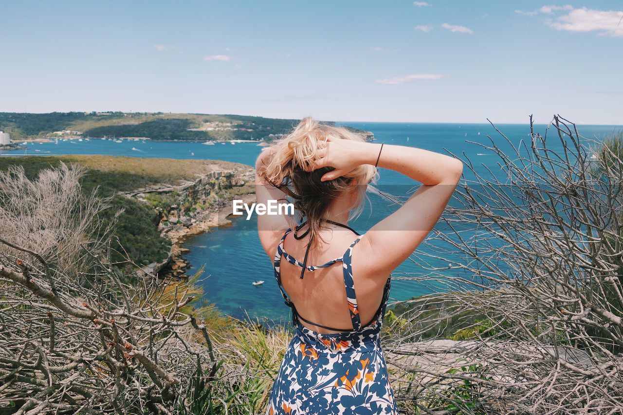 Rear view of woman standing against sea at beach