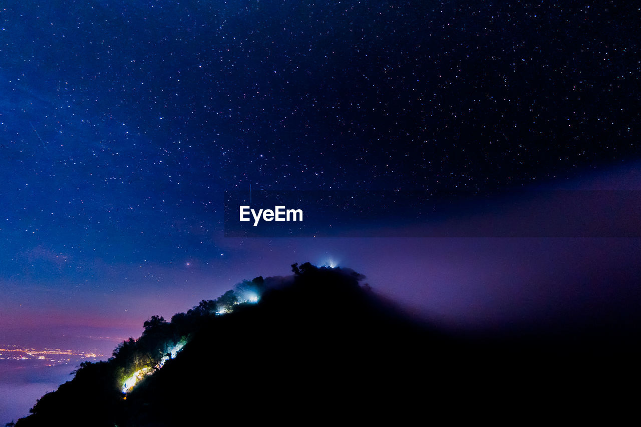 Low angle view of silhouette mountain against sky at night