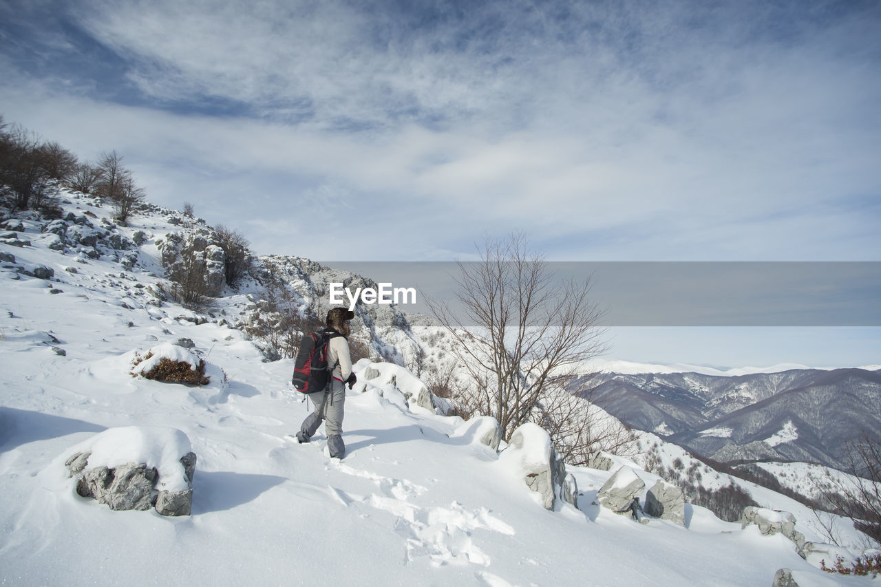 Person on snowcapped mountain against sky