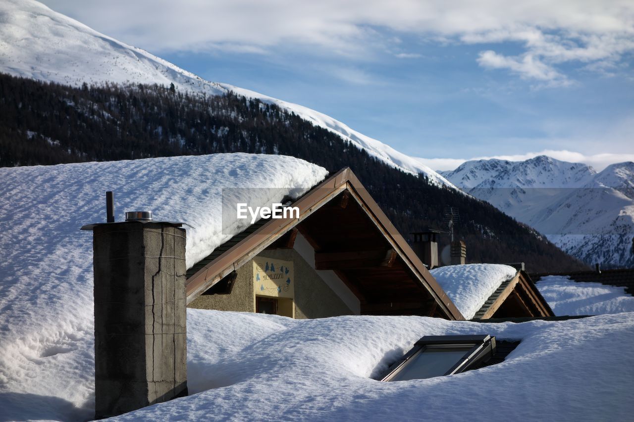 Built structure on snow covered mountain against sky