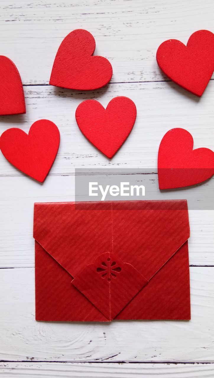 Red heart shape and envelope on table