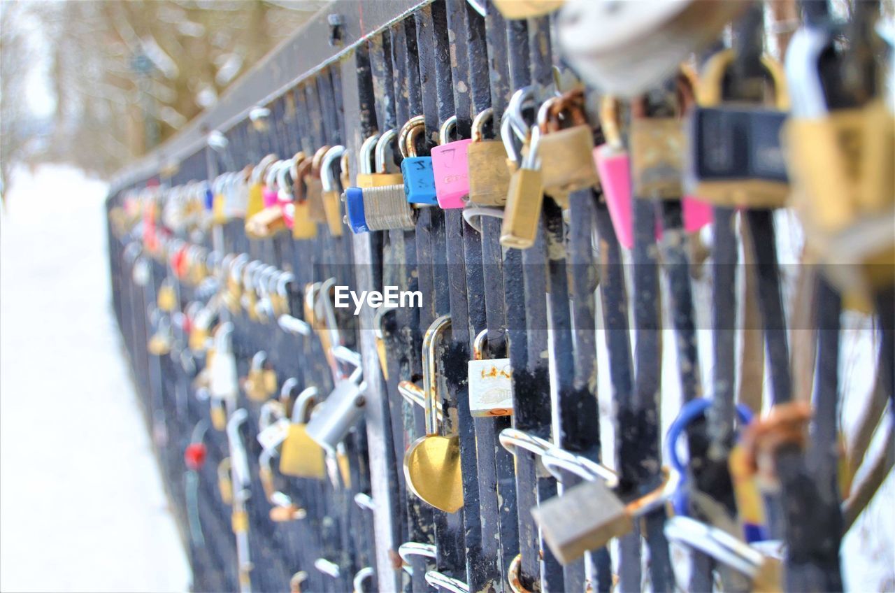 CLOSE-UP OF PADLOCKS HANGING ON METAL RAILING