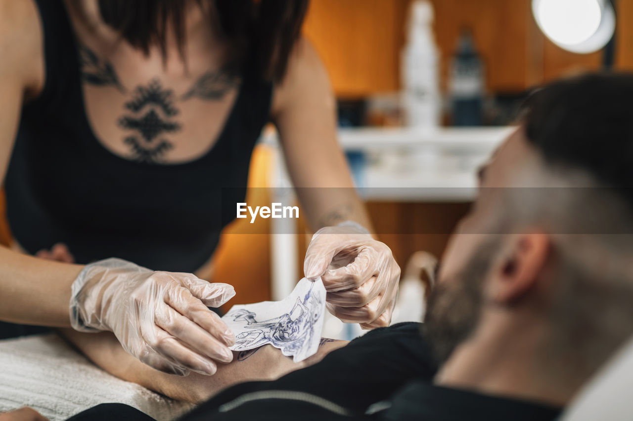 Tattooist removing stencil from a clients arm