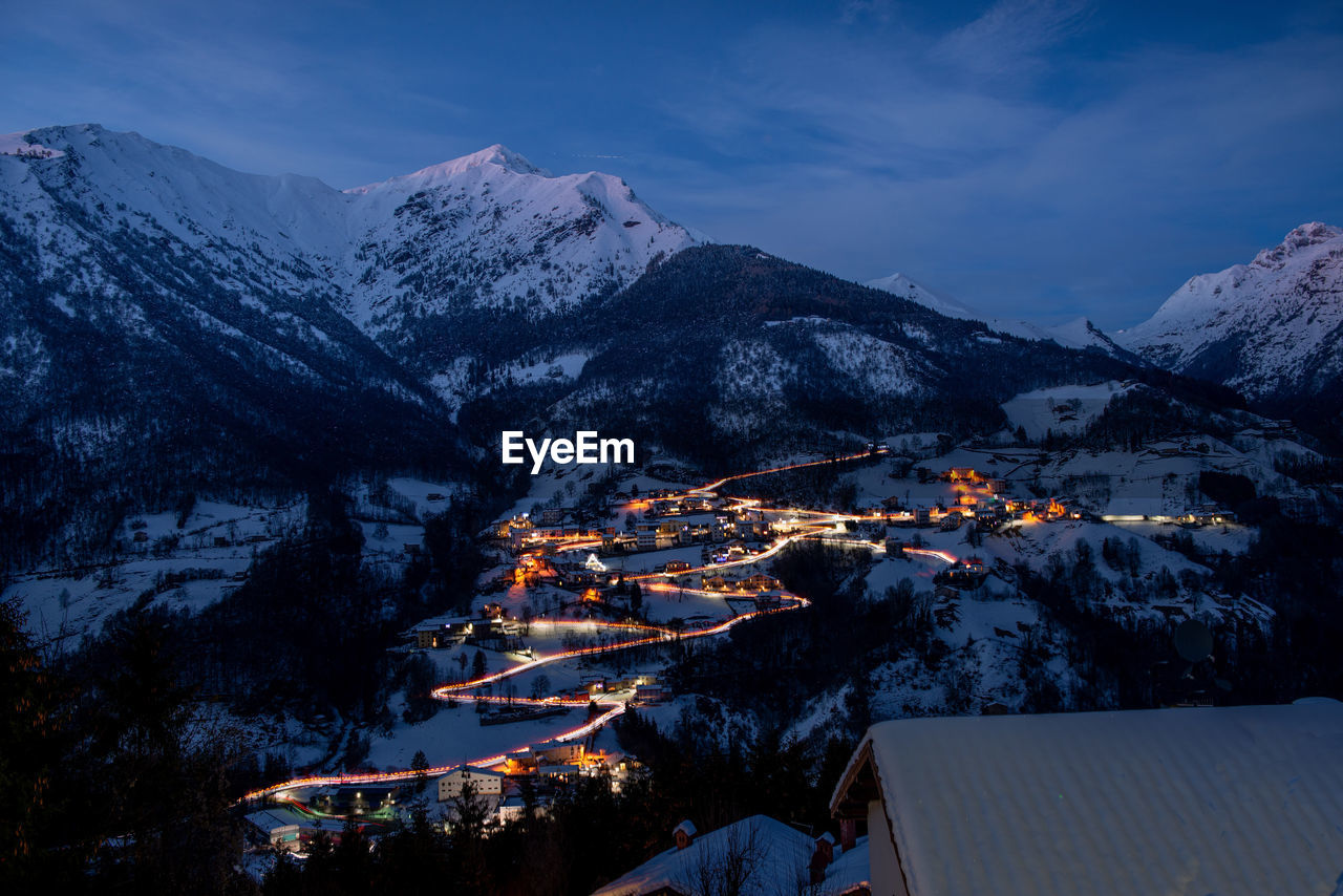 Aerial view of buildings and mountains against sky during winter