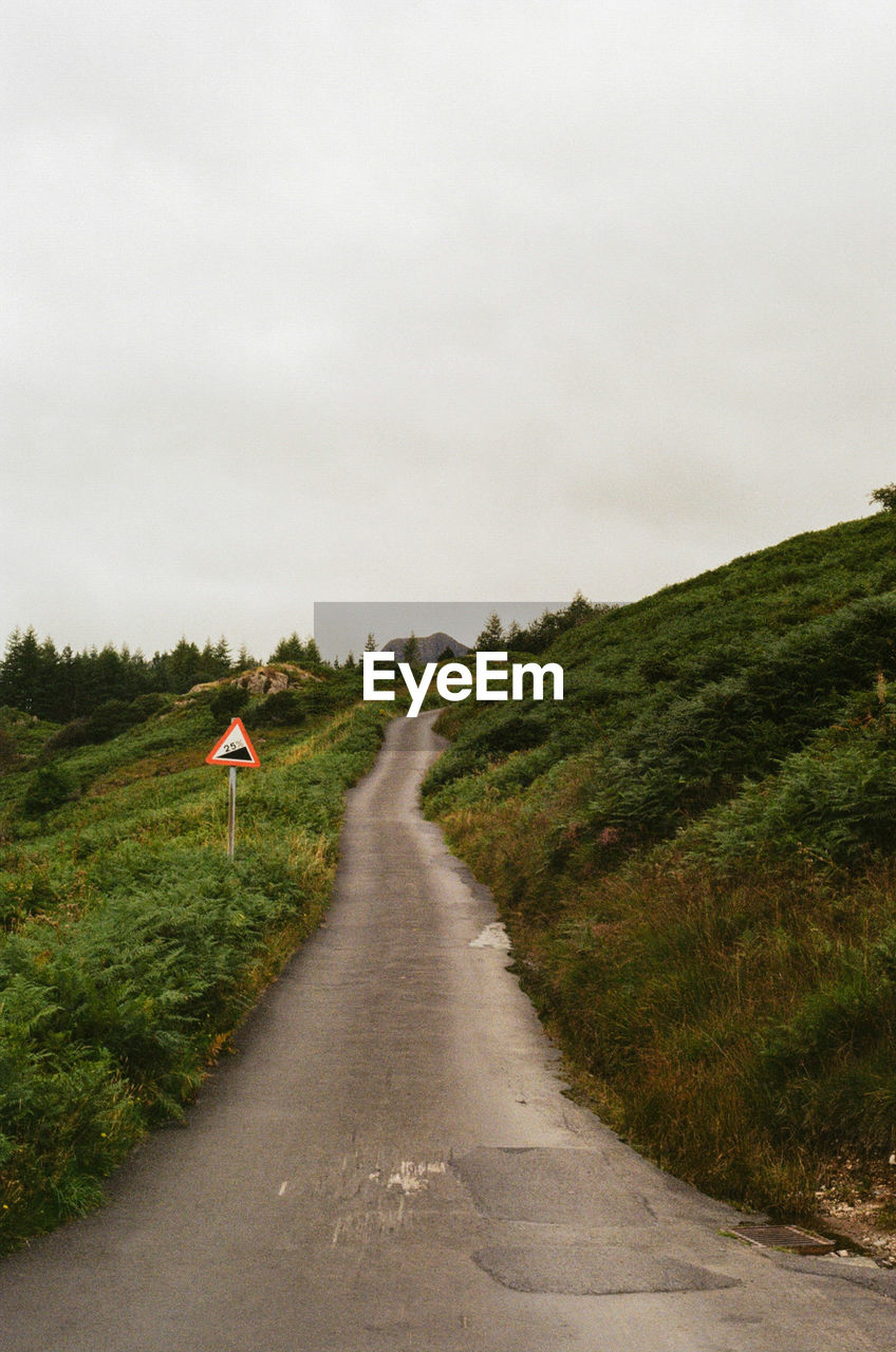 Rear view of man walking on road against sky