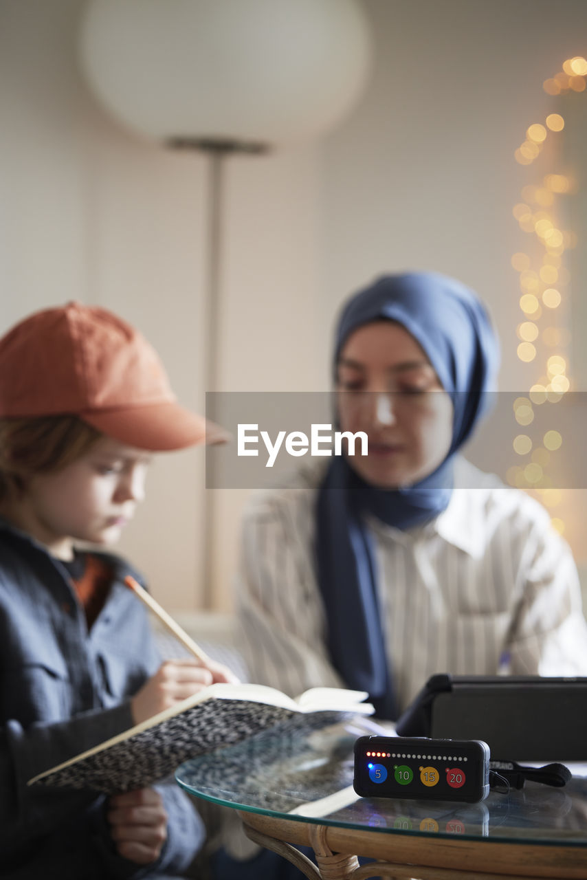 Mother wearing hijab helping son with add or adhd doing homework