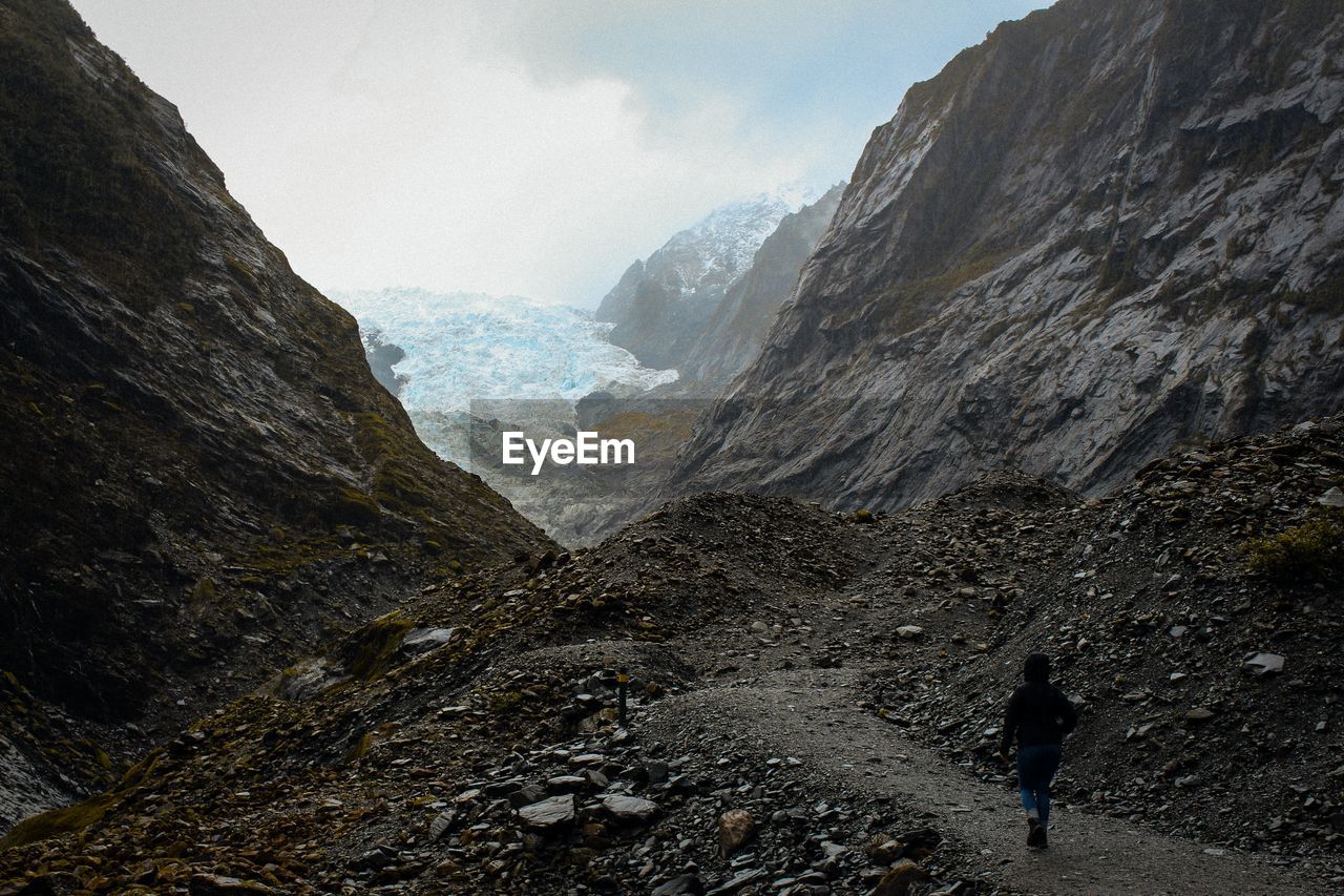 Rear view of woman walking on mountain against sky