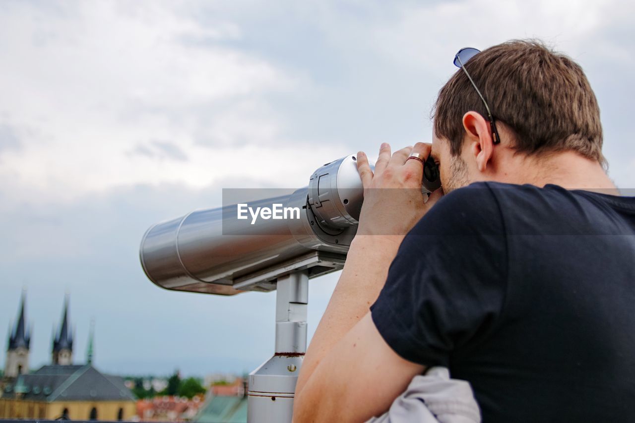 Man looking at city through binoculars