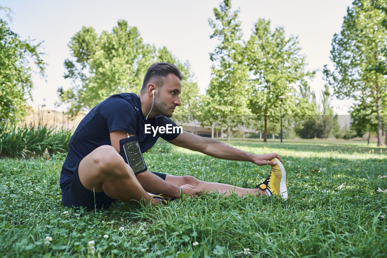 Sportsman stretching muscles sitting on the grass