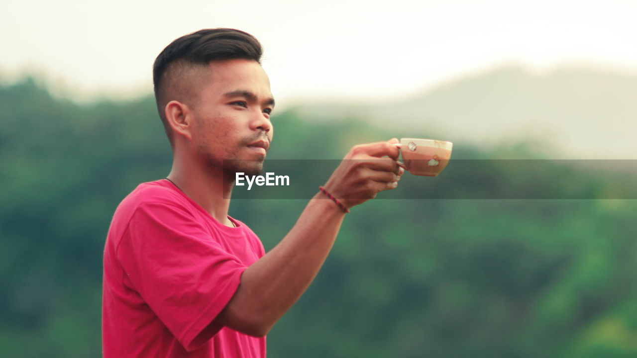 PORTRAIT OF YOUNG MAN STANDING OUTDOORS