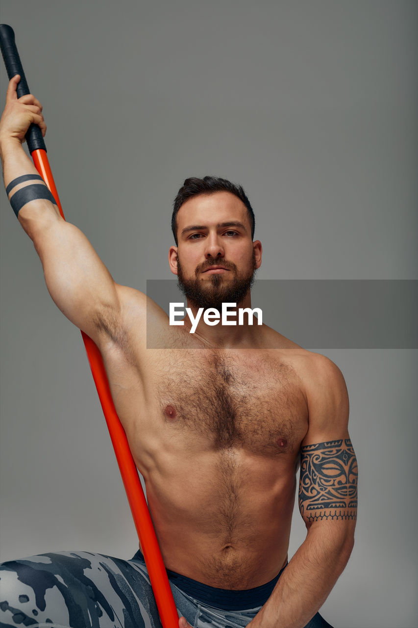 portrait of young man exercising against black background