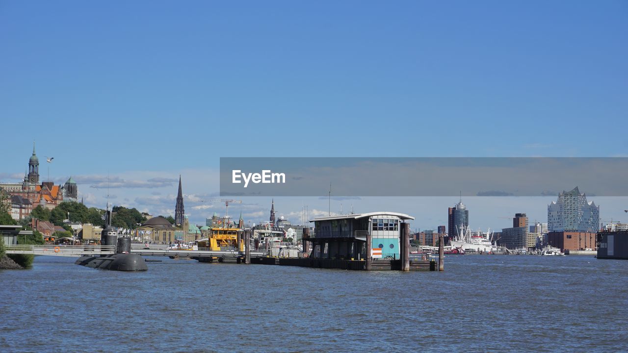 Buildings by sea against clear blue sky