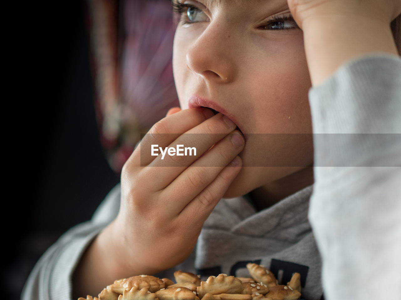 Close-up of bored boy eating biscuits at home