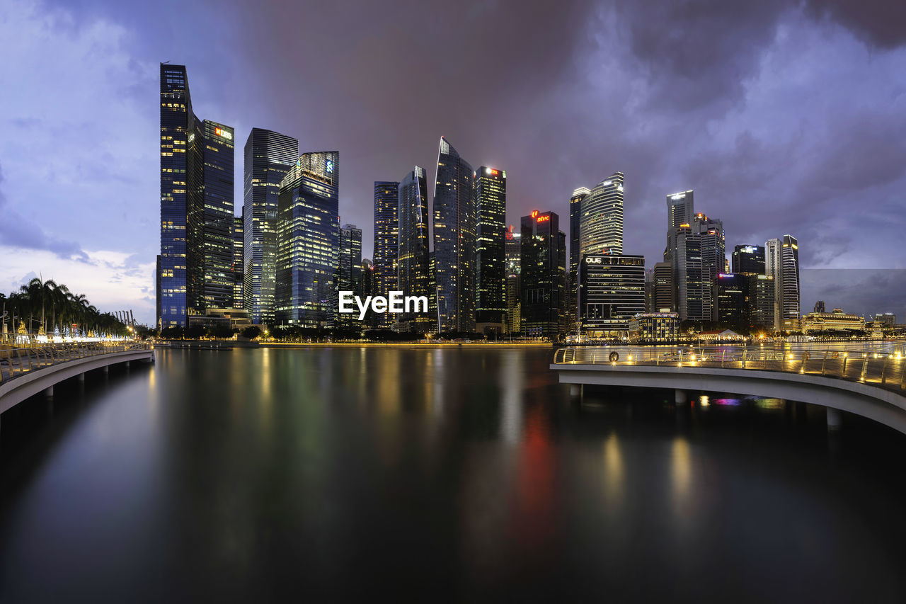 Illuminated buildings by lake in city at night