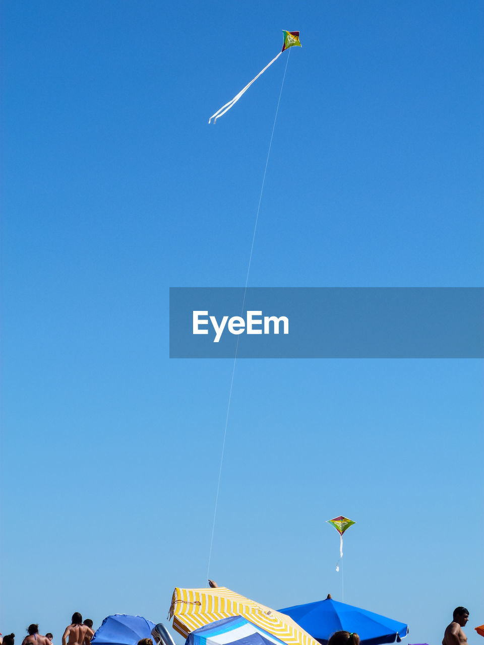 LOW ANGLE VIEW OF MEN AGAINST CLEAR BLUE SKY