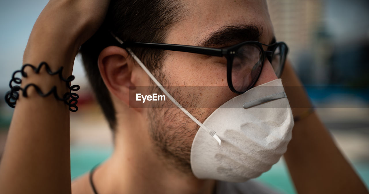 Close-up portrait of young man wearing eyeglasses and a mask