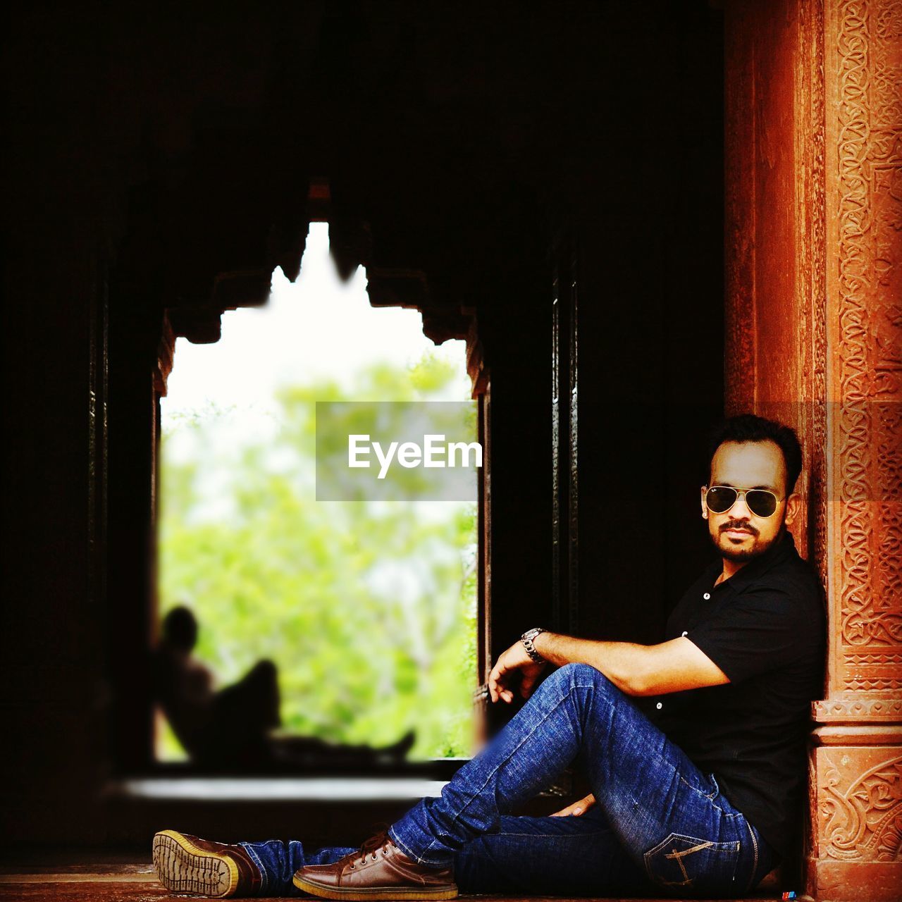 PORTRAIT OF MAN SITTING AT WINDOW OF BUILDING