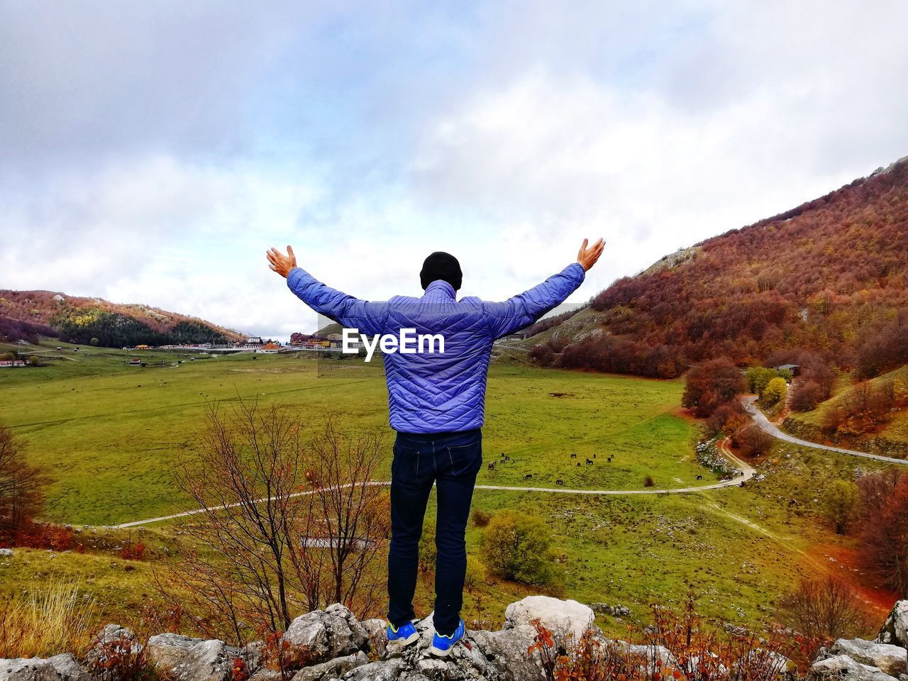 Man from behind with open arms enjoys nature in solitude