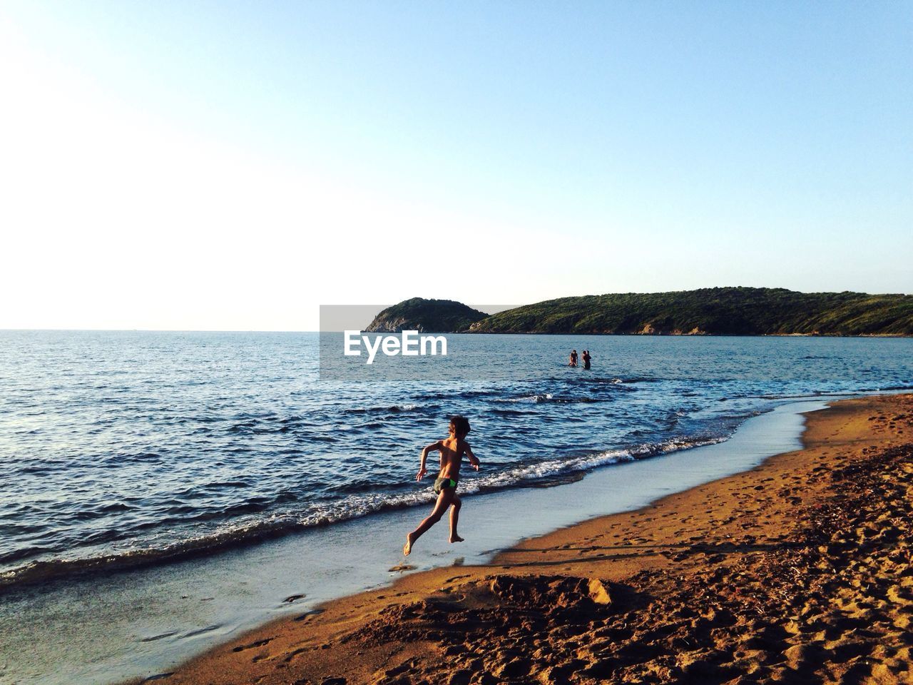 Full length rear view of boy running on beach