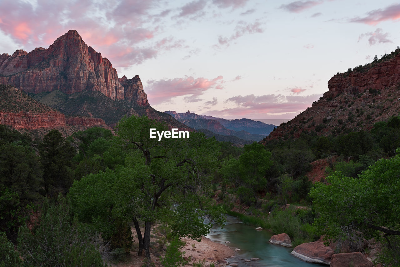 Scenic view of river amidst mountains against sky during sunset