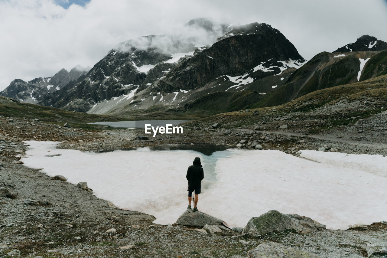 Rear view of person on snowcapped mountain against sky