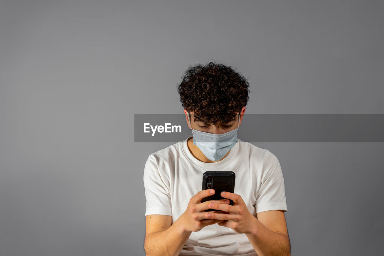 MAN HOLDING SMART PHONE AGAINST WHITE BACKGROUND