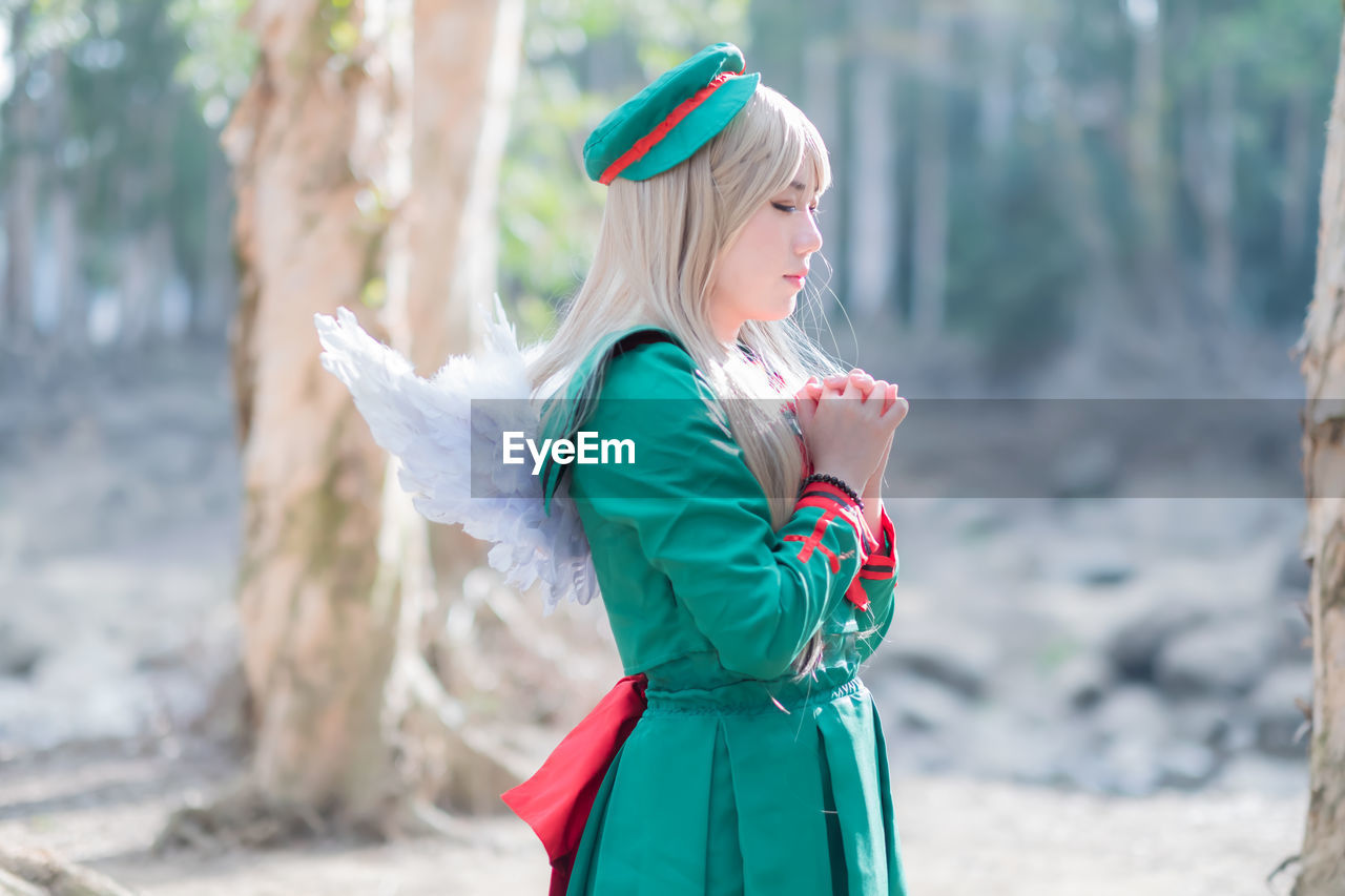 Side view of woman in angel costume standing outdoors