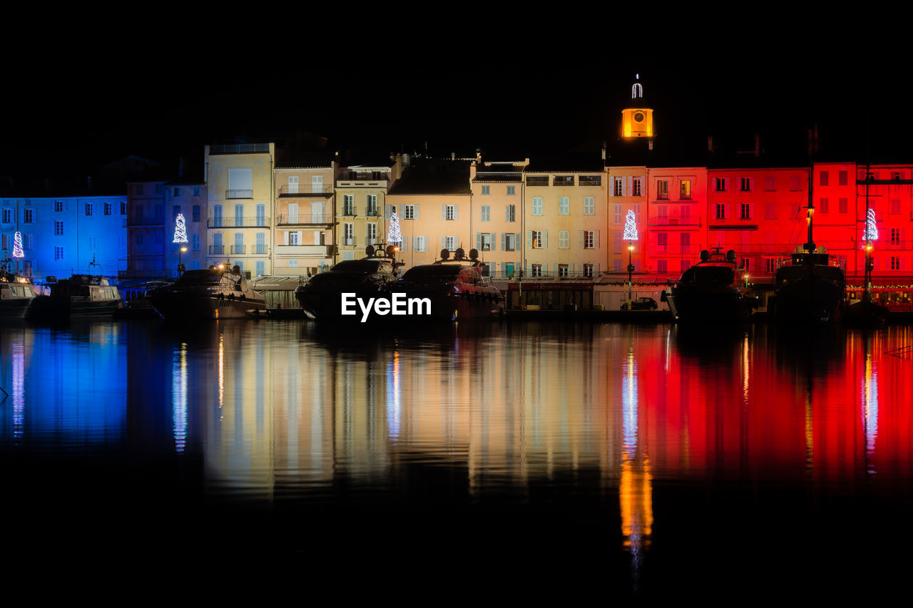 Reflection of illuminated buildings on river in city at night