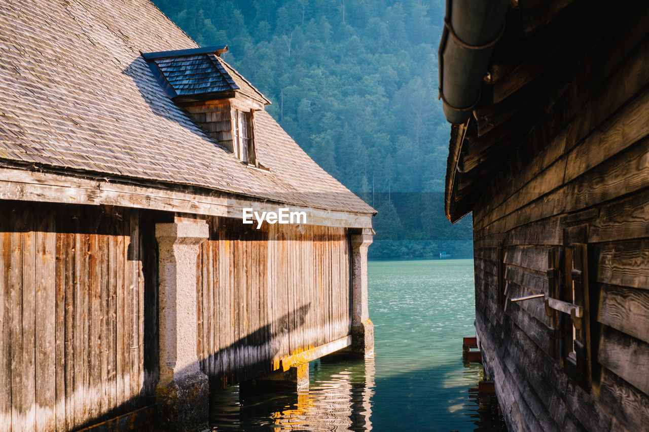 Wooden posts on sea by building against sky