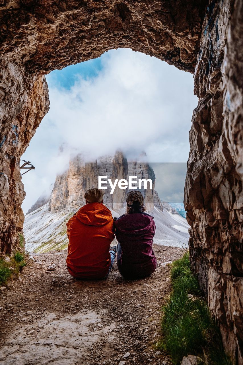 Rear view of couple sitting on cliff