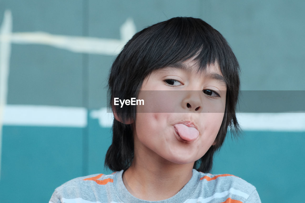 Close-up of boy sticking out tongue while looking away