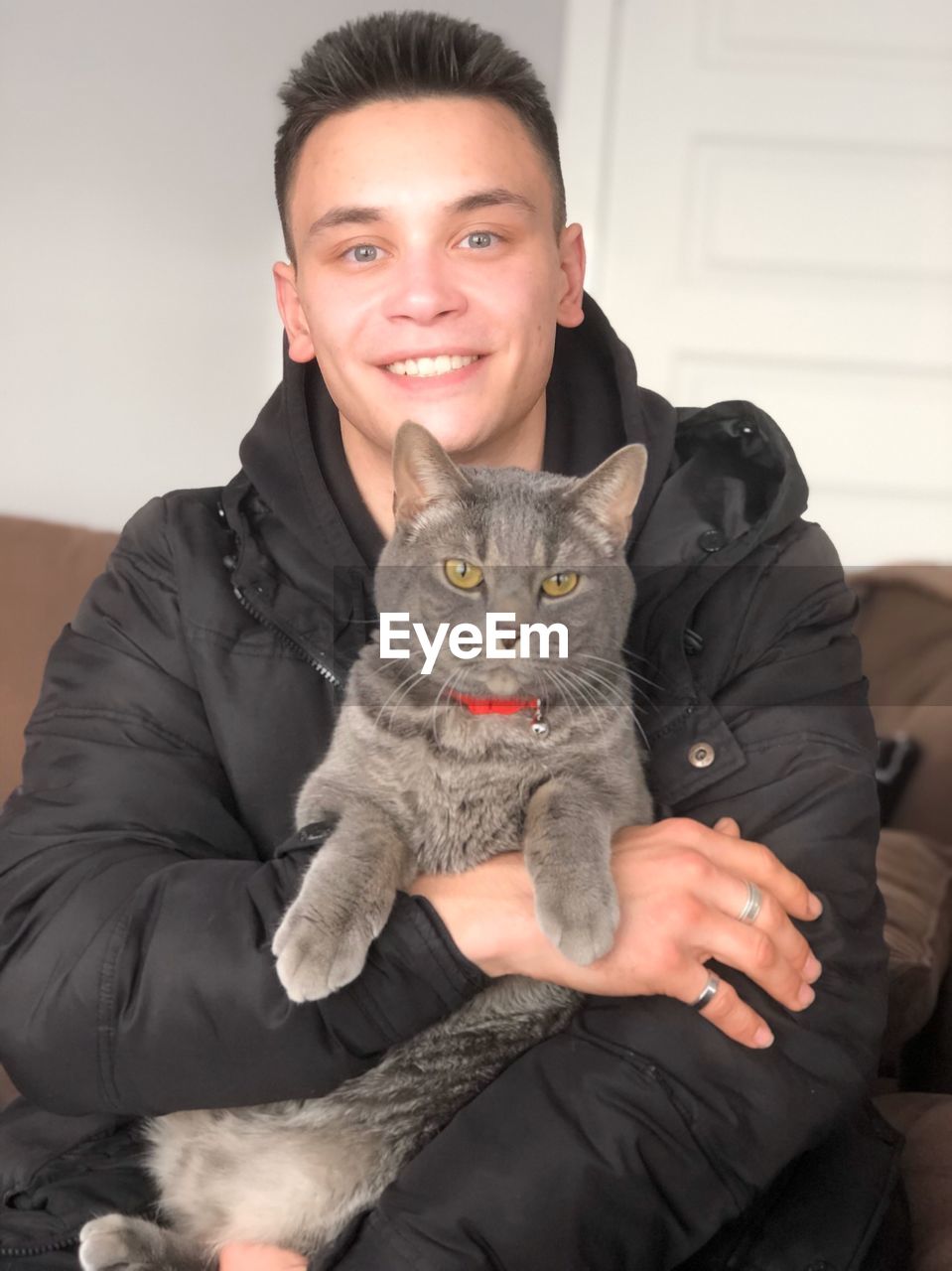 Portrait of smiling young man with cat sitting at home