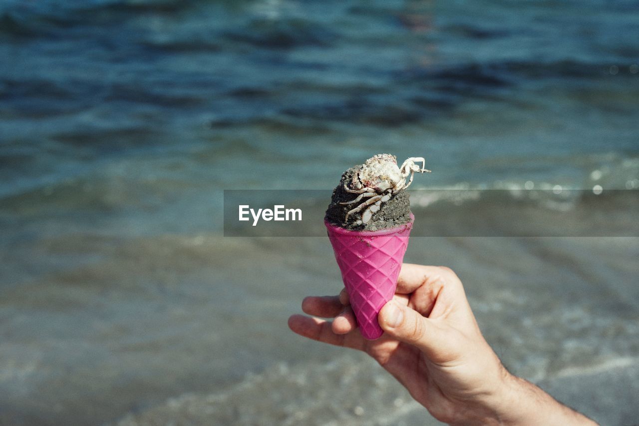 Person holding ice cream cone at beach
