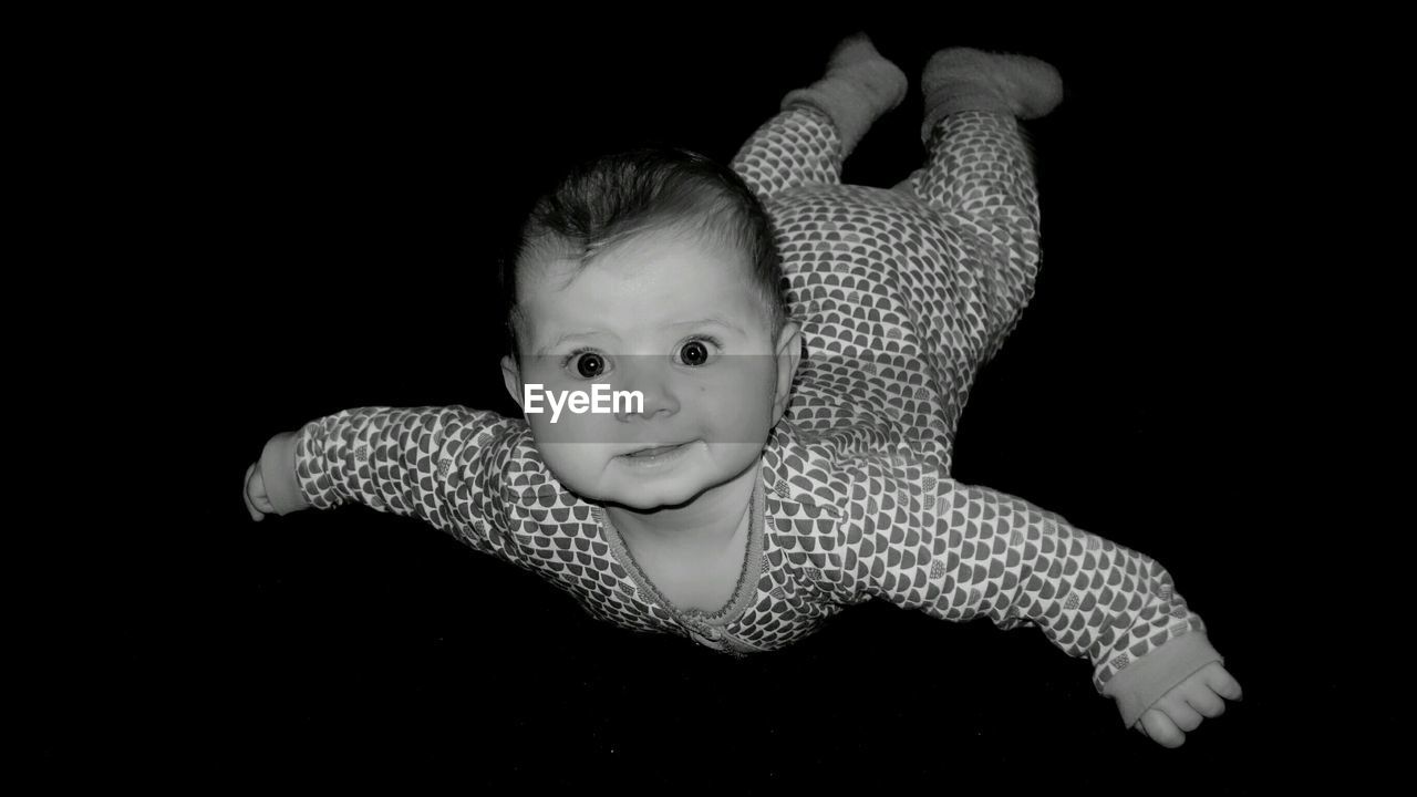 High angle view portrait of baby lying on black background