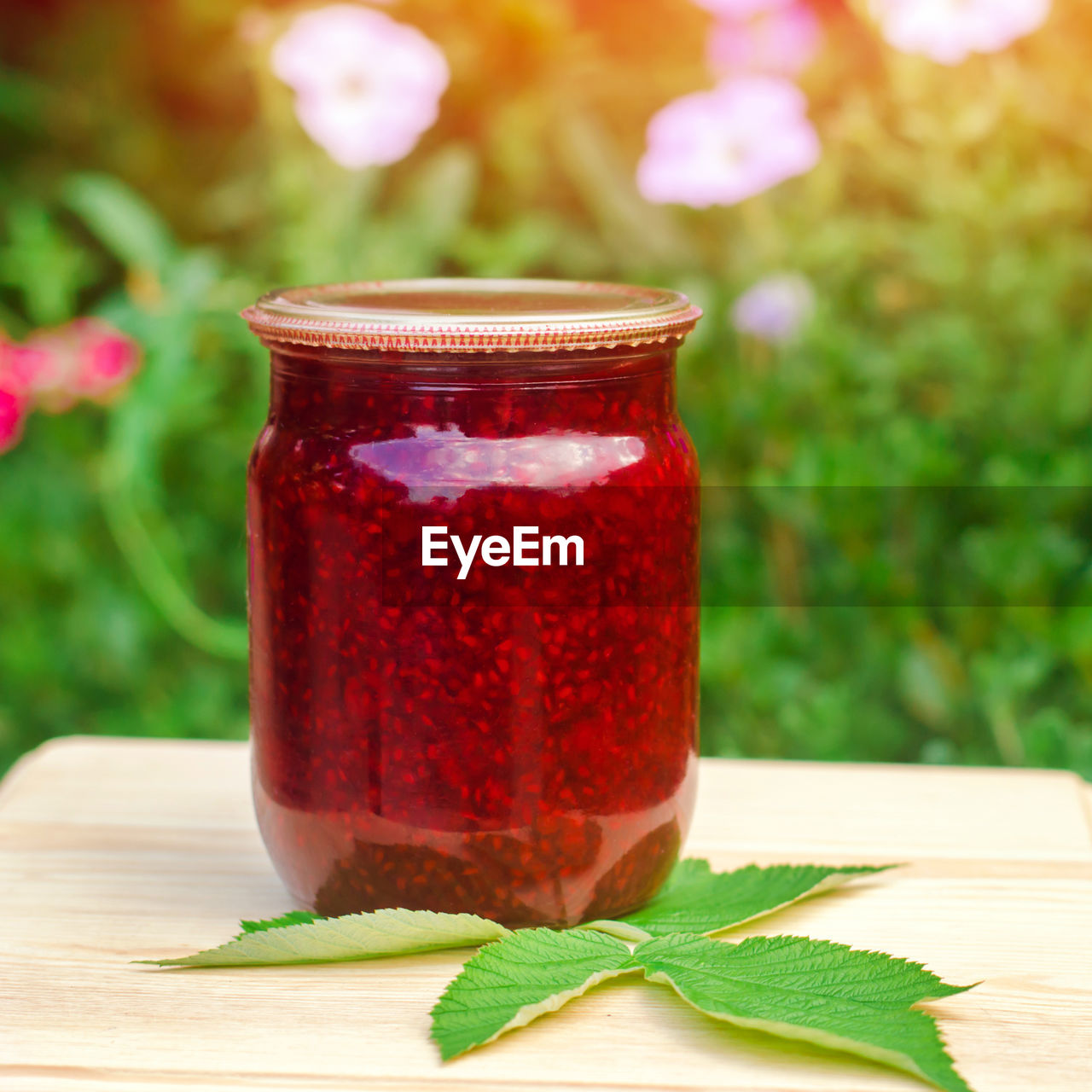 Banks with fragrant homemade raspberry jam in the garden. summer harvest.