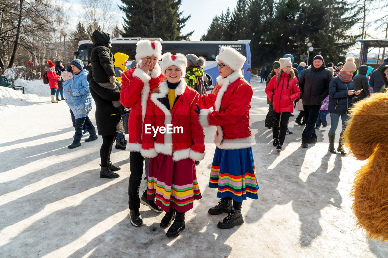 group of people, clothing, crowd, large group of people, winter, nature, day, cold temperature, men, adult, celebration, snow, tree, women, festival, sports, outdoors, sunlight, walking, winter sports, warm clothing, person, tradition, full length, togetherness, costume
