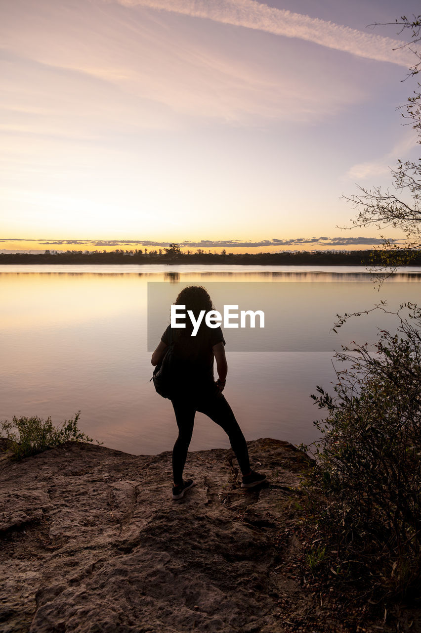 Traveler woman walking by the lake during sunset.