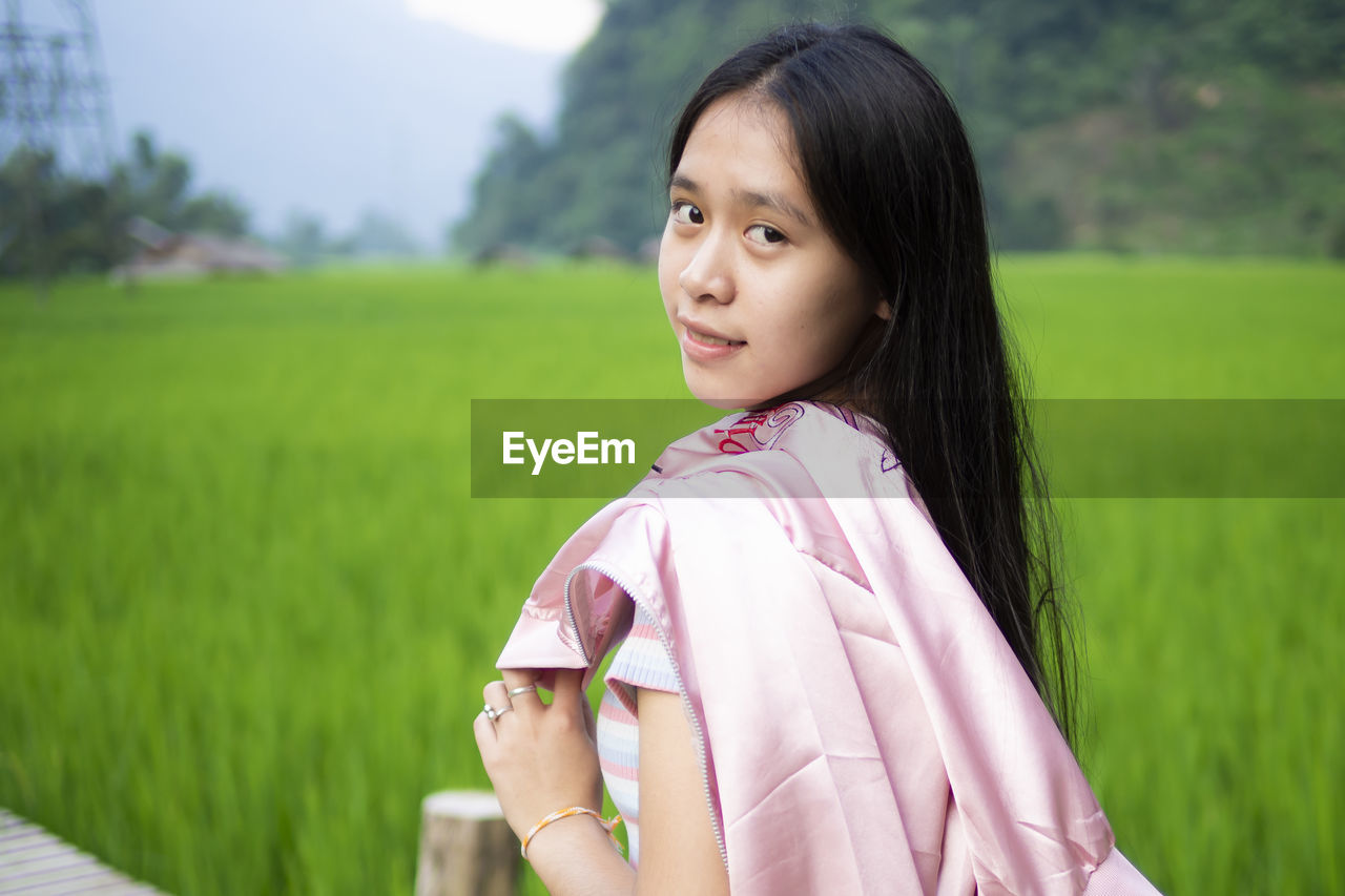 PORTRAIT OF WOMAN STANDING ON FIELD DURING RAINY SEASON