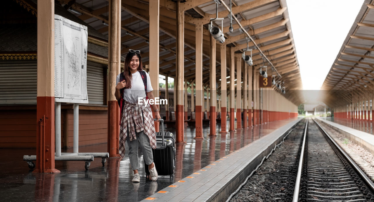 Portrait traveler assian woman walking and waits train on railway platform.