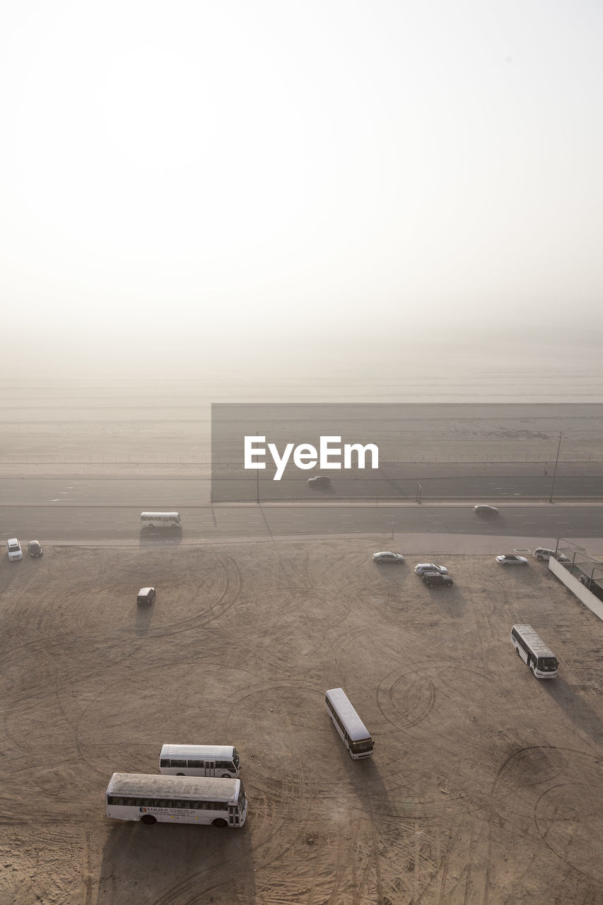 HIGH ANGLE VIEW OF CARS ON LANDSCAPE AGAINST SKY