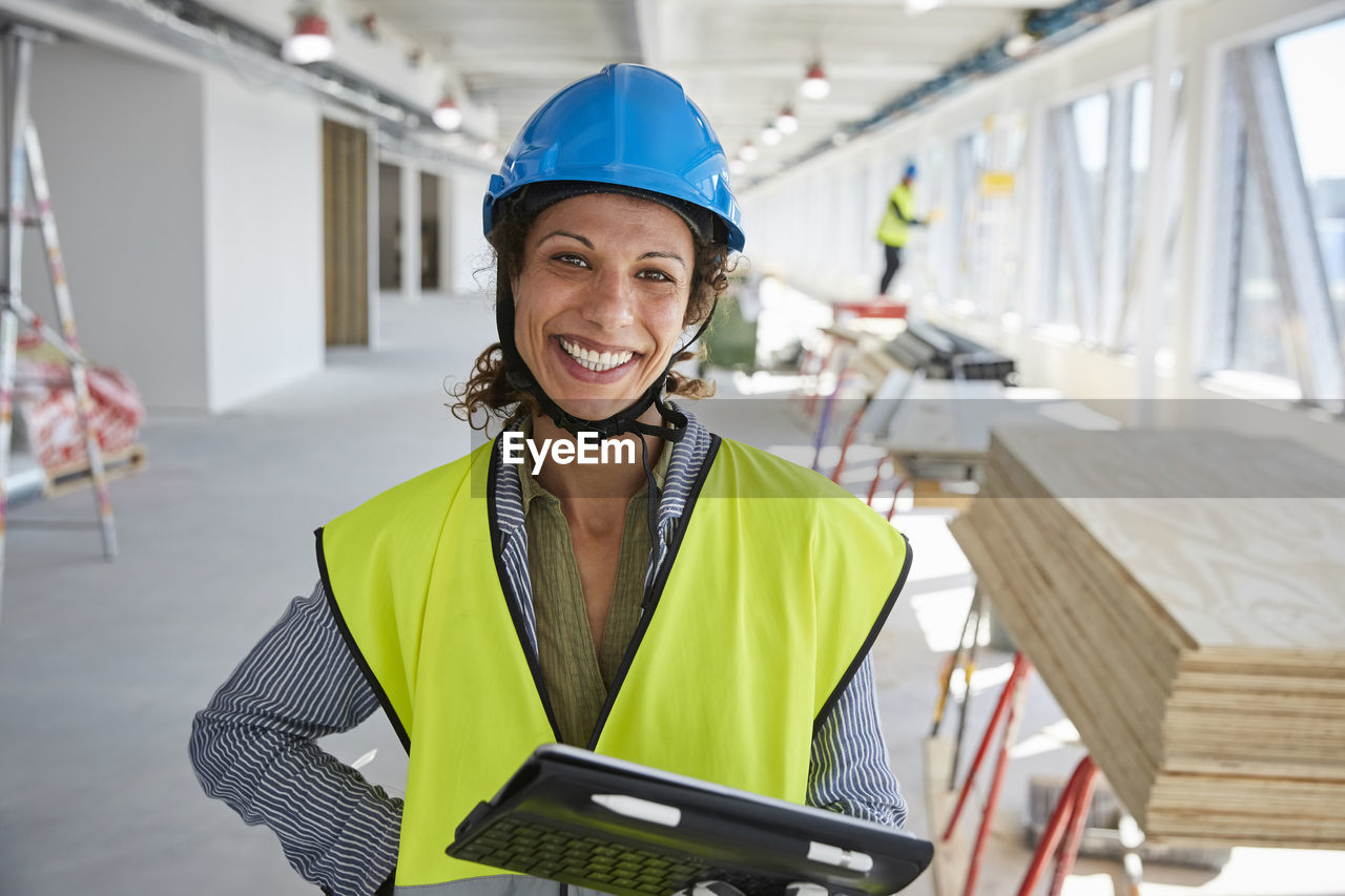 Portrait of smiling female engineer with digital tablet standing at construction site