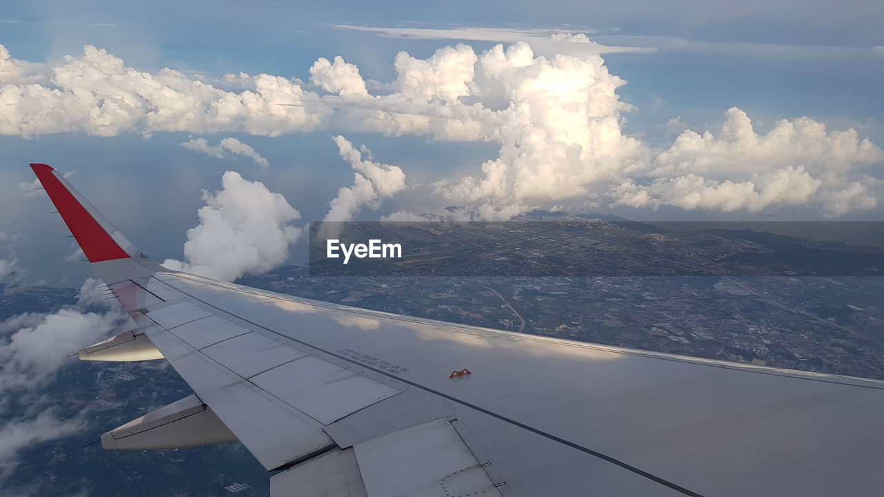 AERIAL VIEW OF AIRPLANE FLYING OVER CLOUDS