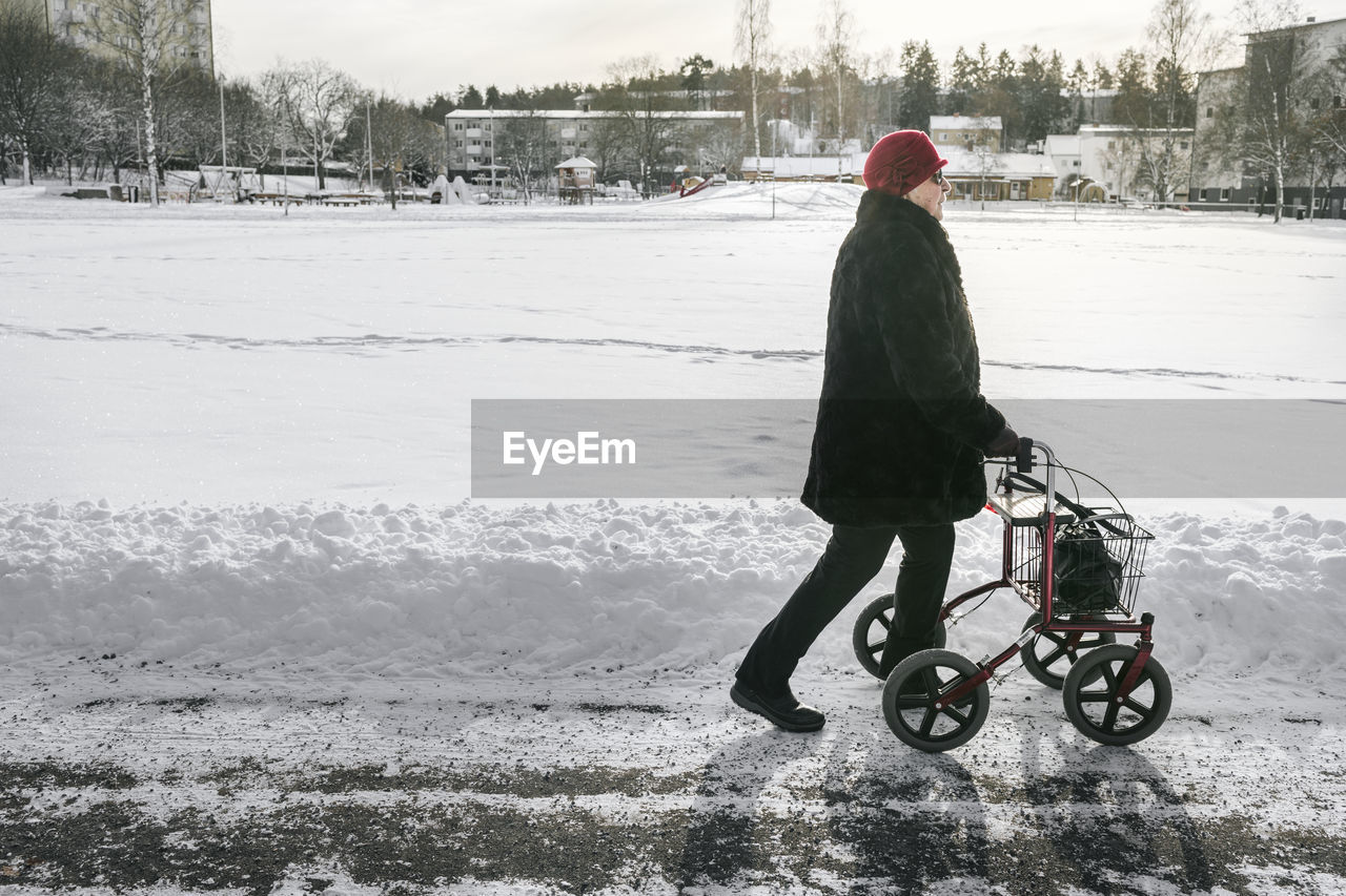 Senior woman with walking frame having walk at winter