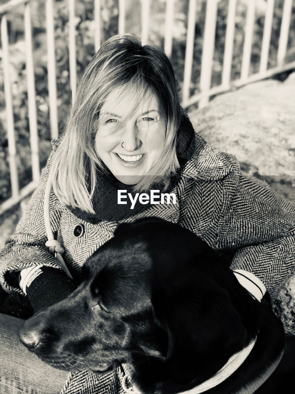 Portrait of smiling woman with dog sitting outdoors