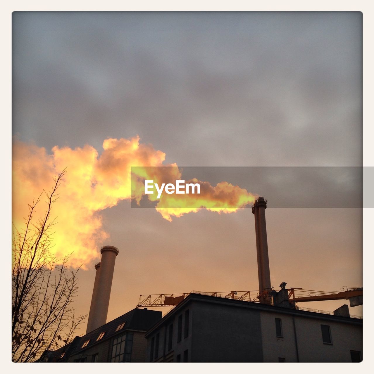 LOW ANGLE VIEW OF SMOKE STACKS AGAINST CLOUDY SKY