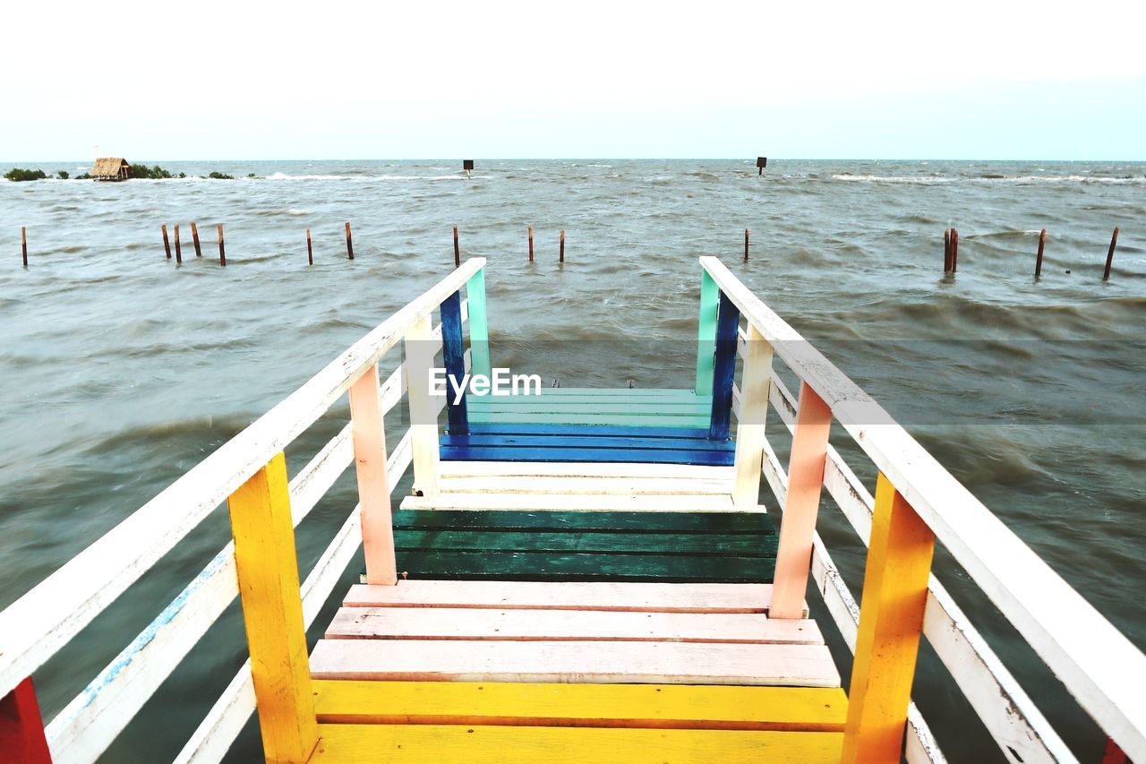 Empty pier on beach against sky