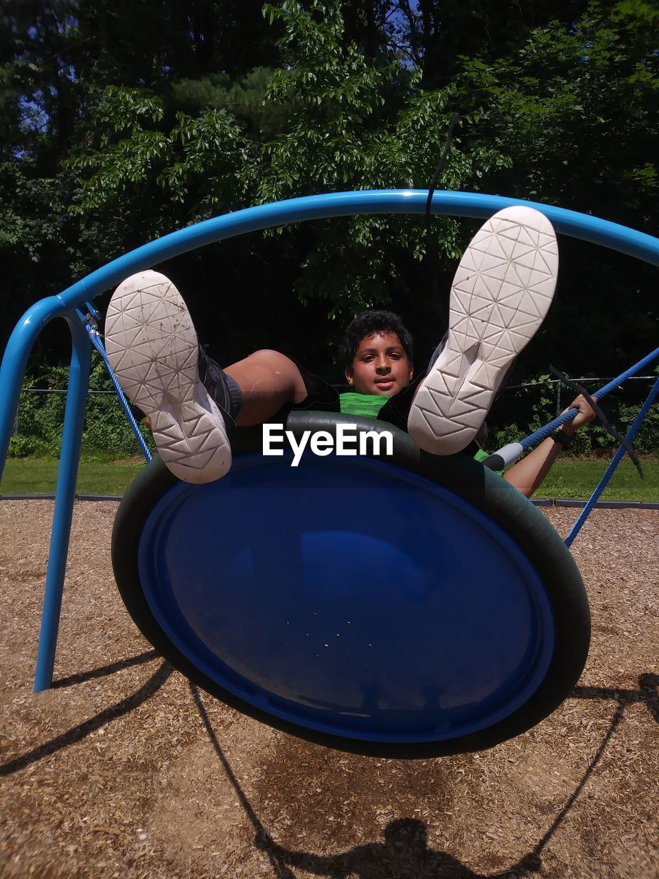 Portrait of boy sitting on play equipment at park