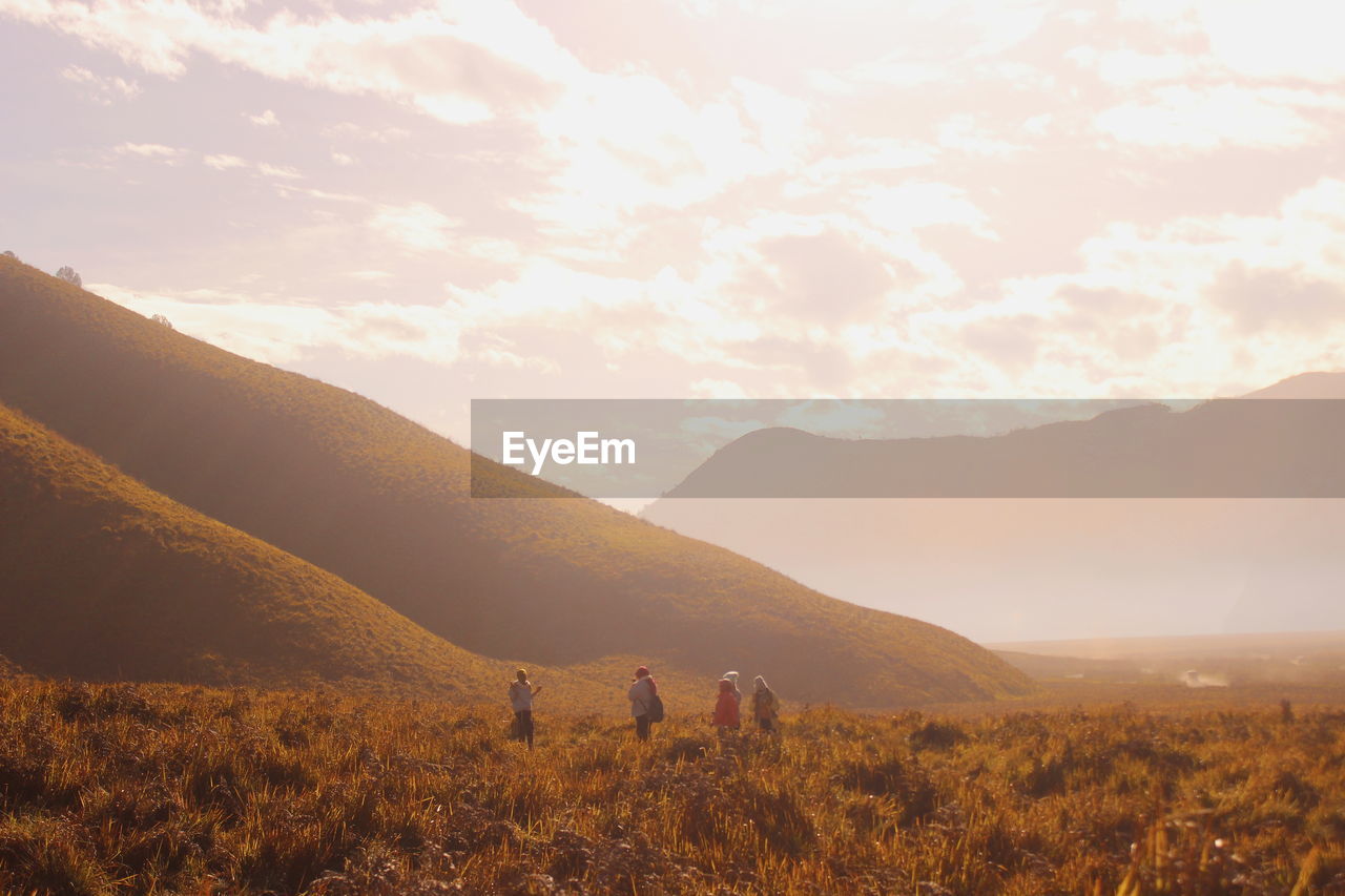 People on field by mountains against sky