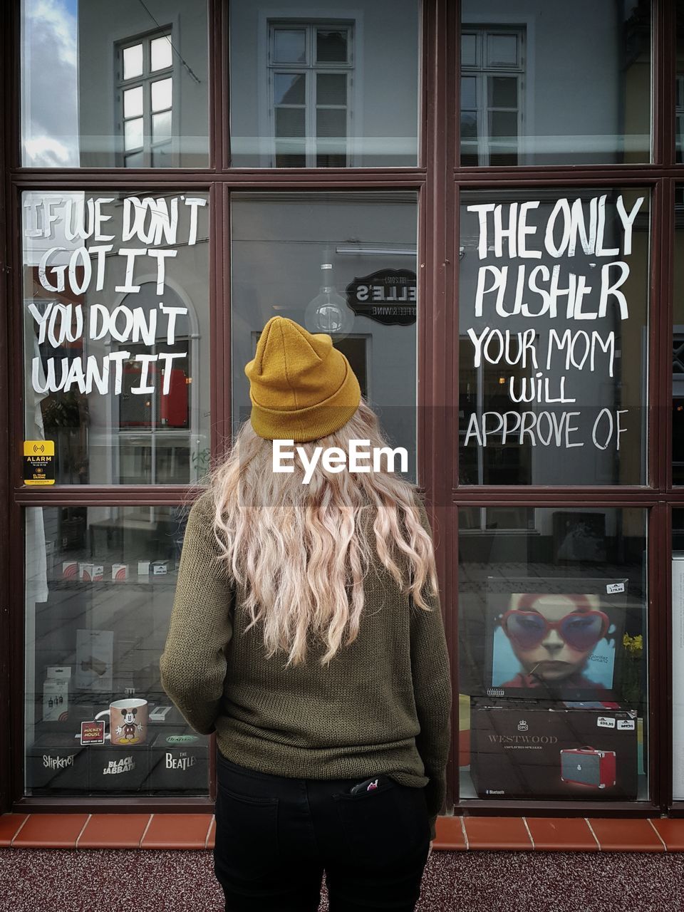 REAR VIEW OF WOMAN STANDING AT STORE