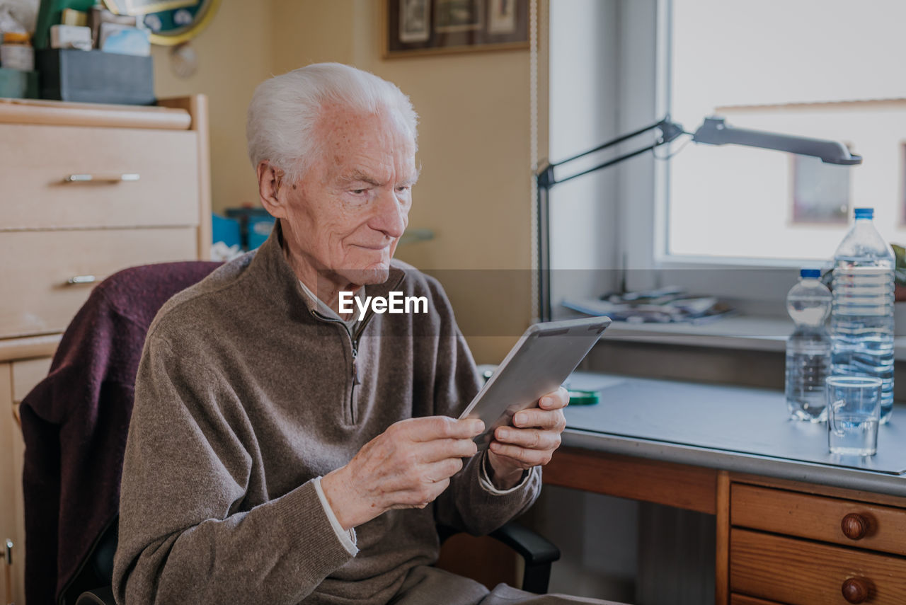 Man using mobile phone while sitting on table